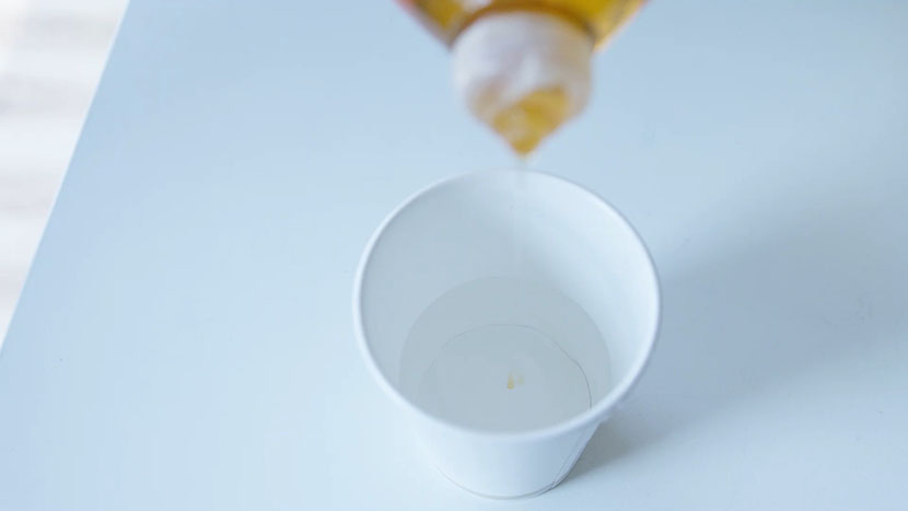 Pouring a couple drops of dish soap into distilled water.