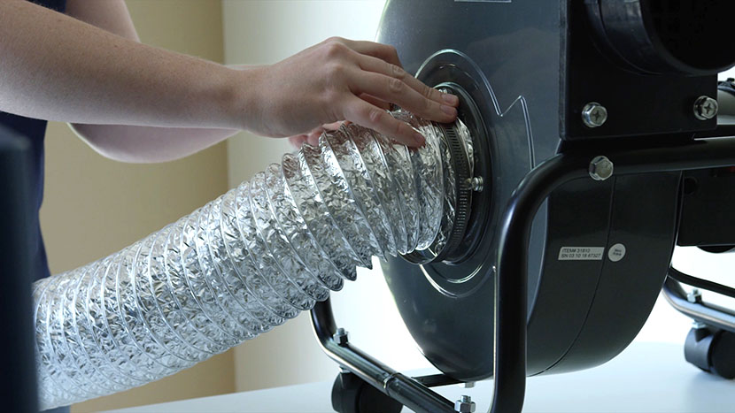 An air ducting tube being attached to the intake port of an external blower unit.