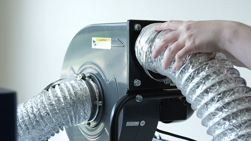 An air ducting tube being attached to the outtake port of an external blower unit.