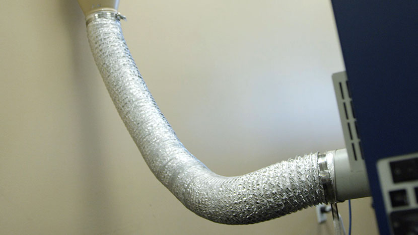 Flexible metal ducting connecting the exhaust port of the laser to the building's ventilation system.