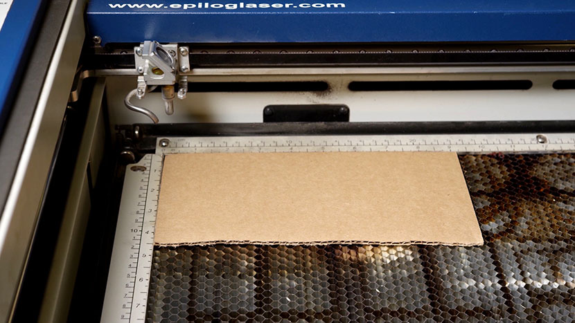 A piece of cardboard in the top-left corner of the Mini/Helix vector cutting grid.