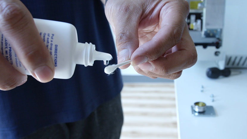 Lens cleaning fluid being applied to a cotton swab.