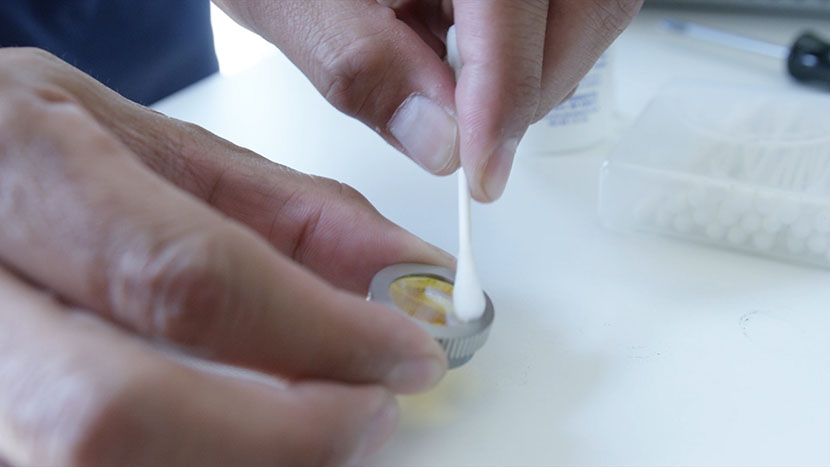 Cleaning the lens with a cotton swab.