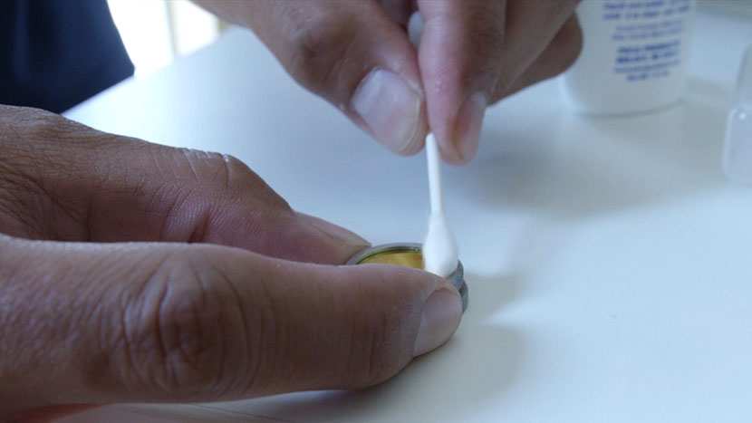 Cleaning the mirror with a cotton swab.