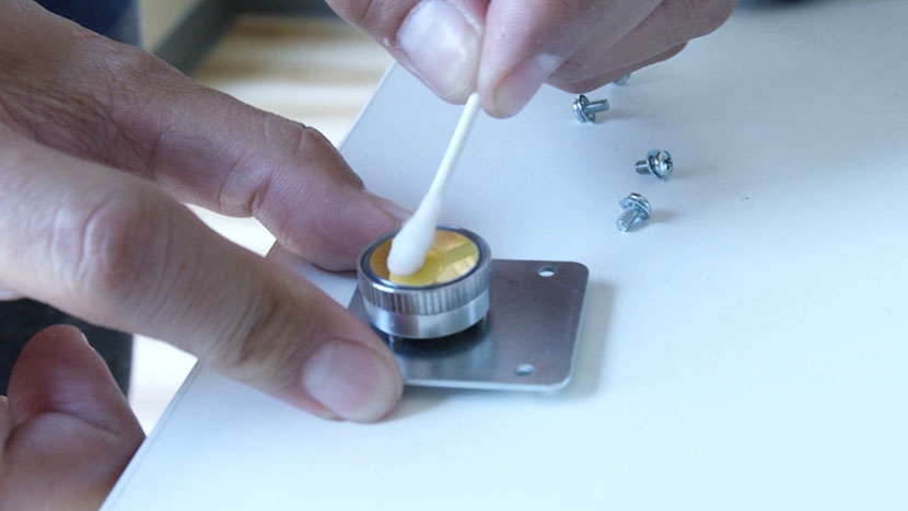 Cleaning the mirror with a cotton swab.