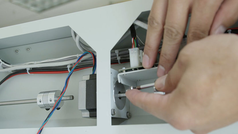 Lifting the fan control board panel to gain access to the two upper mounting screw holes.