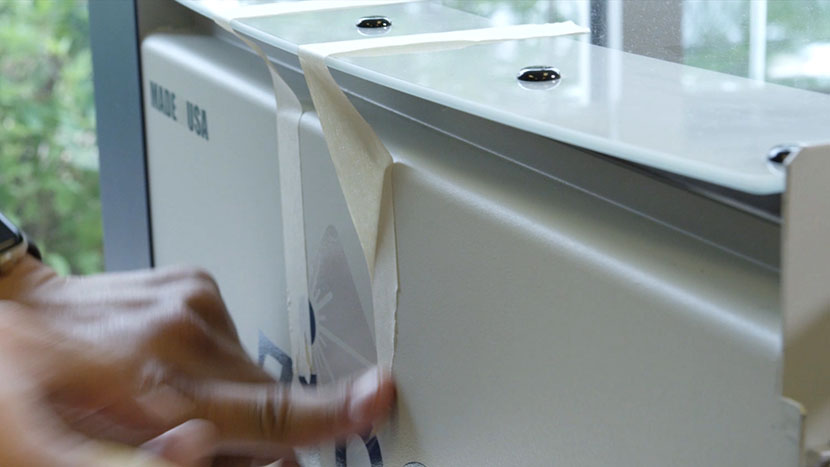 Applying masking tape to the lid of the machine.